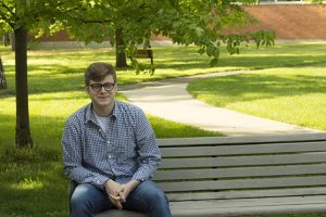 Eric Rhodes sits on a bench on Antioch's campus