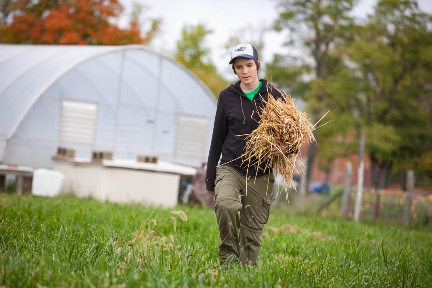 A student carries hay across the Antioch Farm