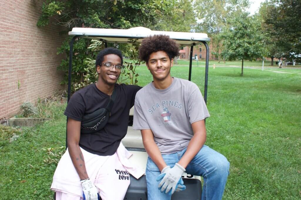 Two current Antioch students sit side-by-side on a golf cart taking in the good vibes on Cummunity Day 2021