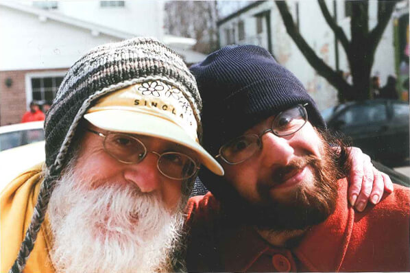 Robert and Seth - two scruffy hippies smile and embrace