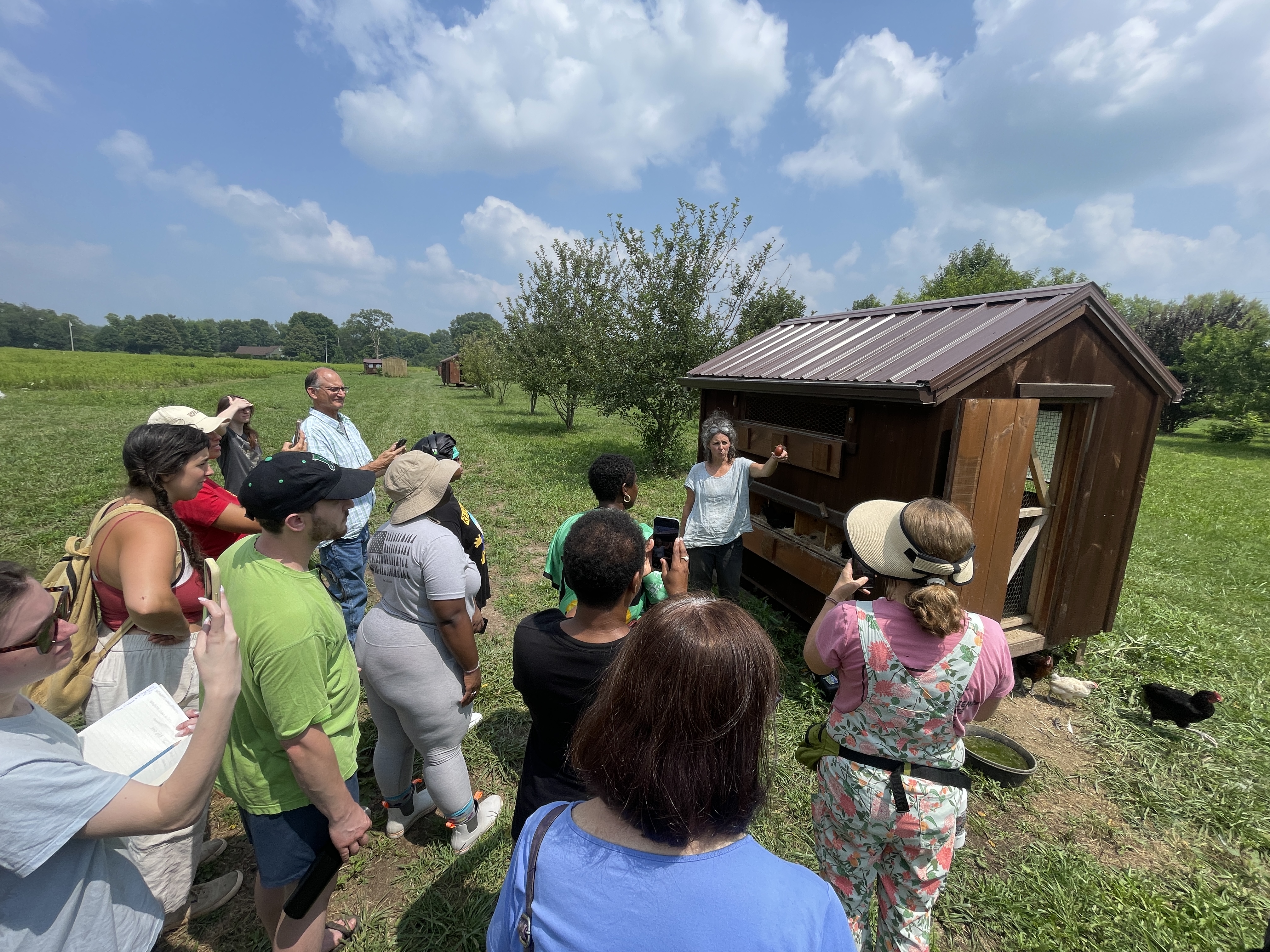 Group gathered at a chicken coop during an egg-collecting demonstration