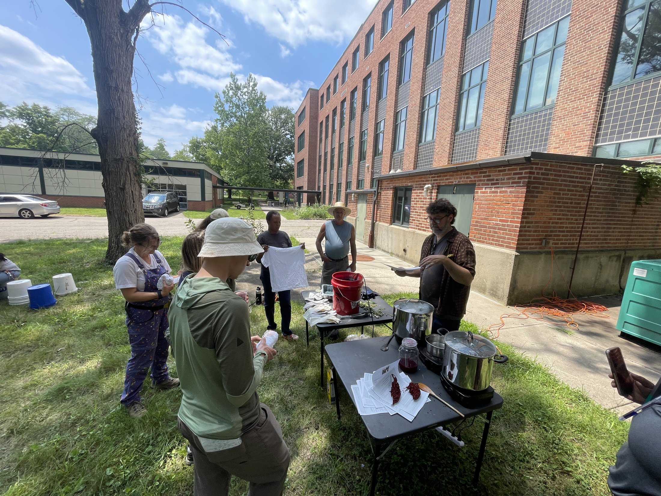 Group gathered outside for a natural-dye demonstration with pots and dyed cloth